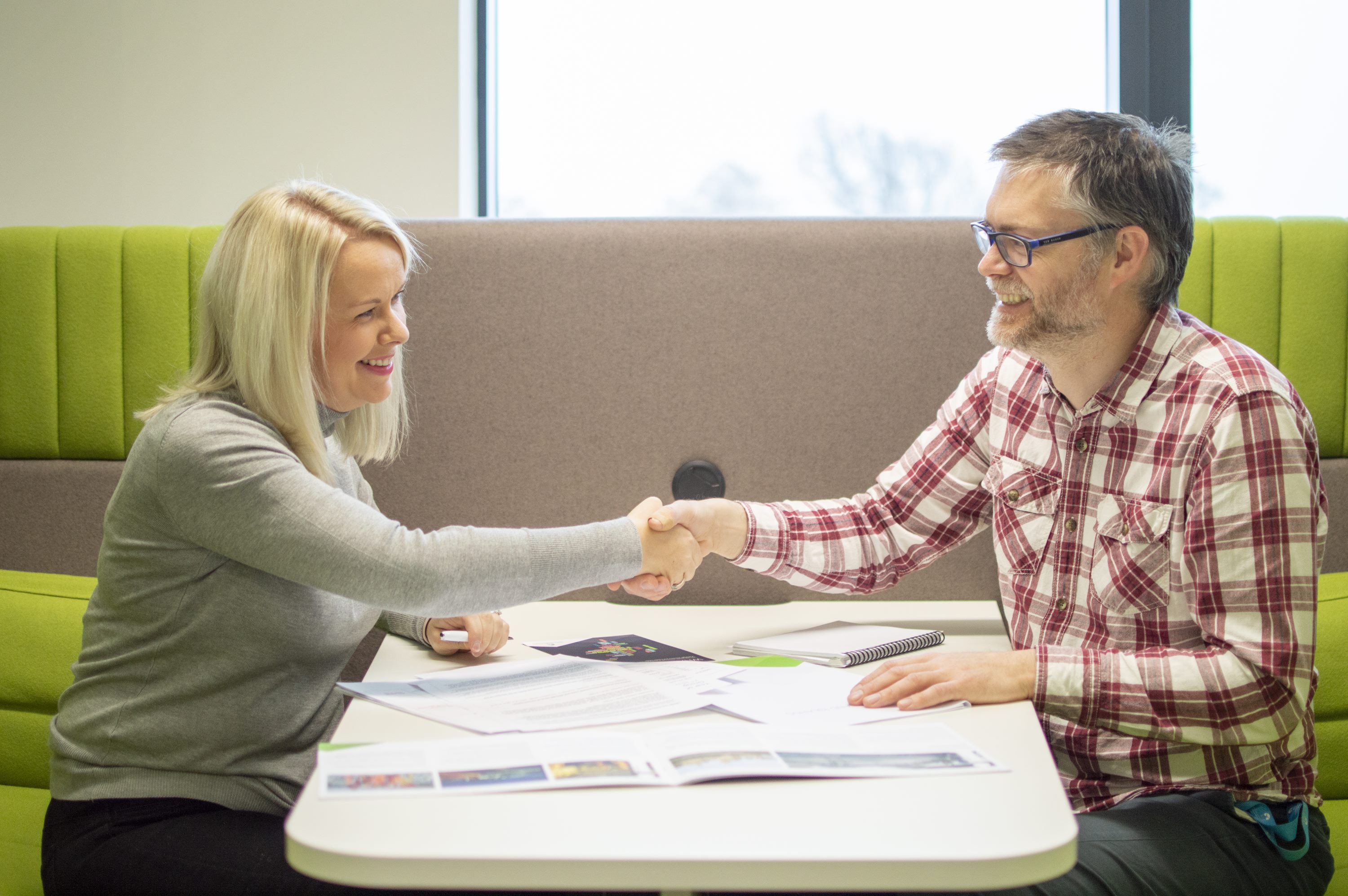 Business associates shaking hands over desk